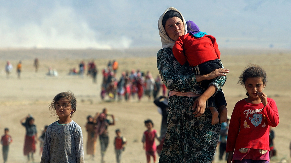 Pessoas deslocadas da seita minoritária Yazidi caminham em direção à fronteira com a Síria, nos arredores da montanha de Sinjar, em 11 de agosto de 2014 [Rodi Said / Reuters]